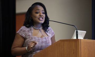 Dr. Kametris L. Weddington, dressed professionally, delivering a presentation to an audience in the J.D. Boyd Library Medgar Wiley Evers Auditorium.